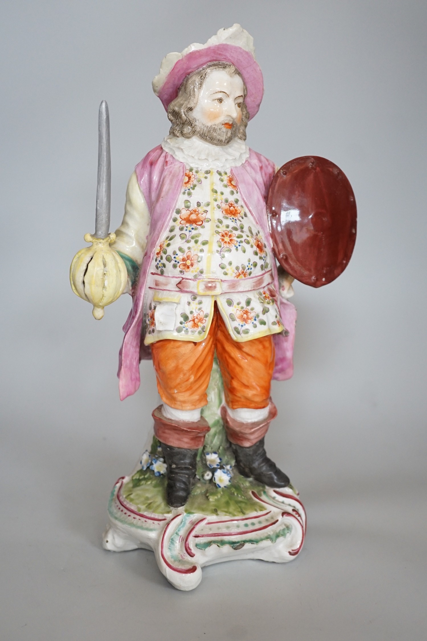 A large Derby figure of Falstaff standing, holding a sword and shield, patch marks, original brass sword, is now a modelled replacement, 39cms high